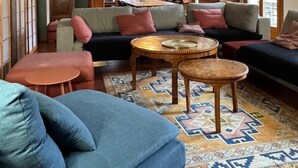 Een gezellige woonkamer met een bank, twee ronde tafels en een kamerkleed met een patroon.