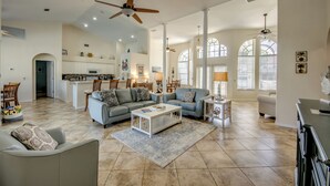 A spacious living room with a large sofa, a coffee table, and a dining area with a chandelier. - Long Water View, Pool, Kayaks, Bikes, Views,116 Reviews! Villa 21 (Cape Coral)