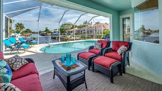 A covered outdoor area with a pool, lounge chairs, and seating. - Long Water View, Pool, Kayaks, Bikes, Views,116 Reviews! Villa 21 (Cape Coral)
