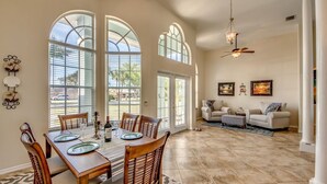 A spacious living room with a dining area, large windows, and a ceiling fan. - Long Water View, Pool, Kayaks, Bikes, Views,116 Reviews! Villa 21 (Cape Coral)
