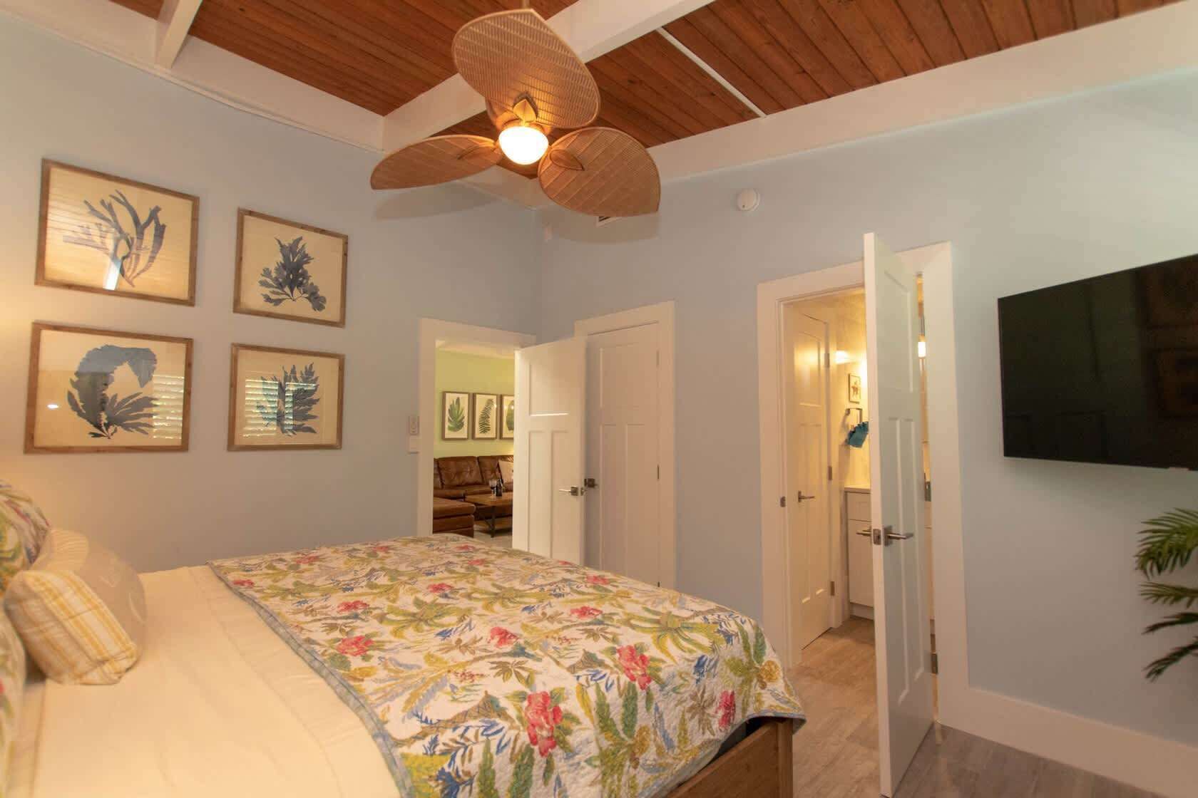 Una camera da letto con un letto, ventilatore a soffitto e televisione a parete.
