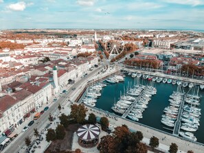 An aerial view of a harbor with boats, a Ferris wheel, and buildings. - Appartement sympa et cosy avec Wi-Fi Gratuit (La Rochelle)