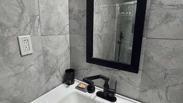 A bathroom with a white sink, black faucet, and a mirror with a black frame.