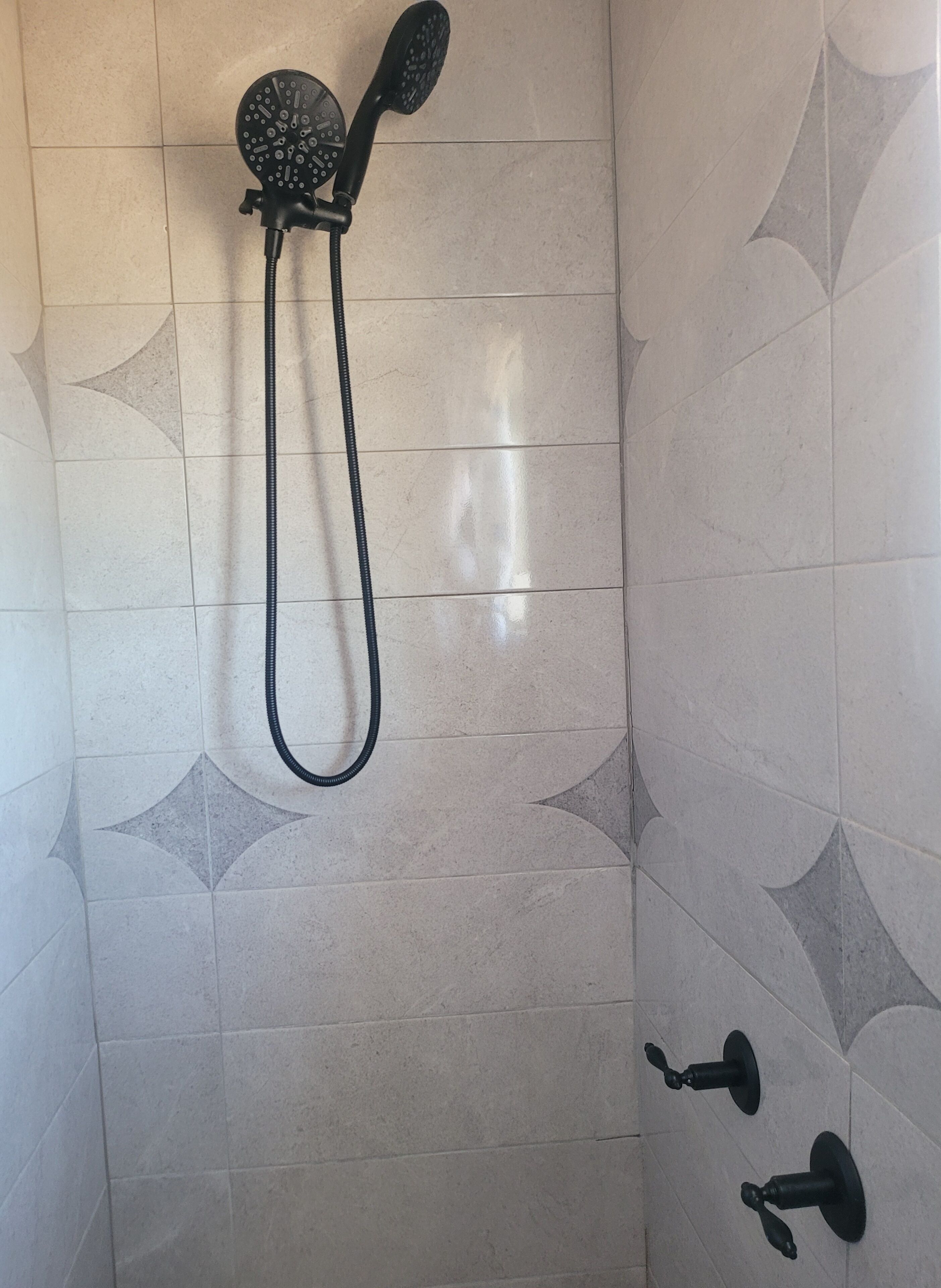 A shower with a handheld showerhead and a wall-mounted faucet.