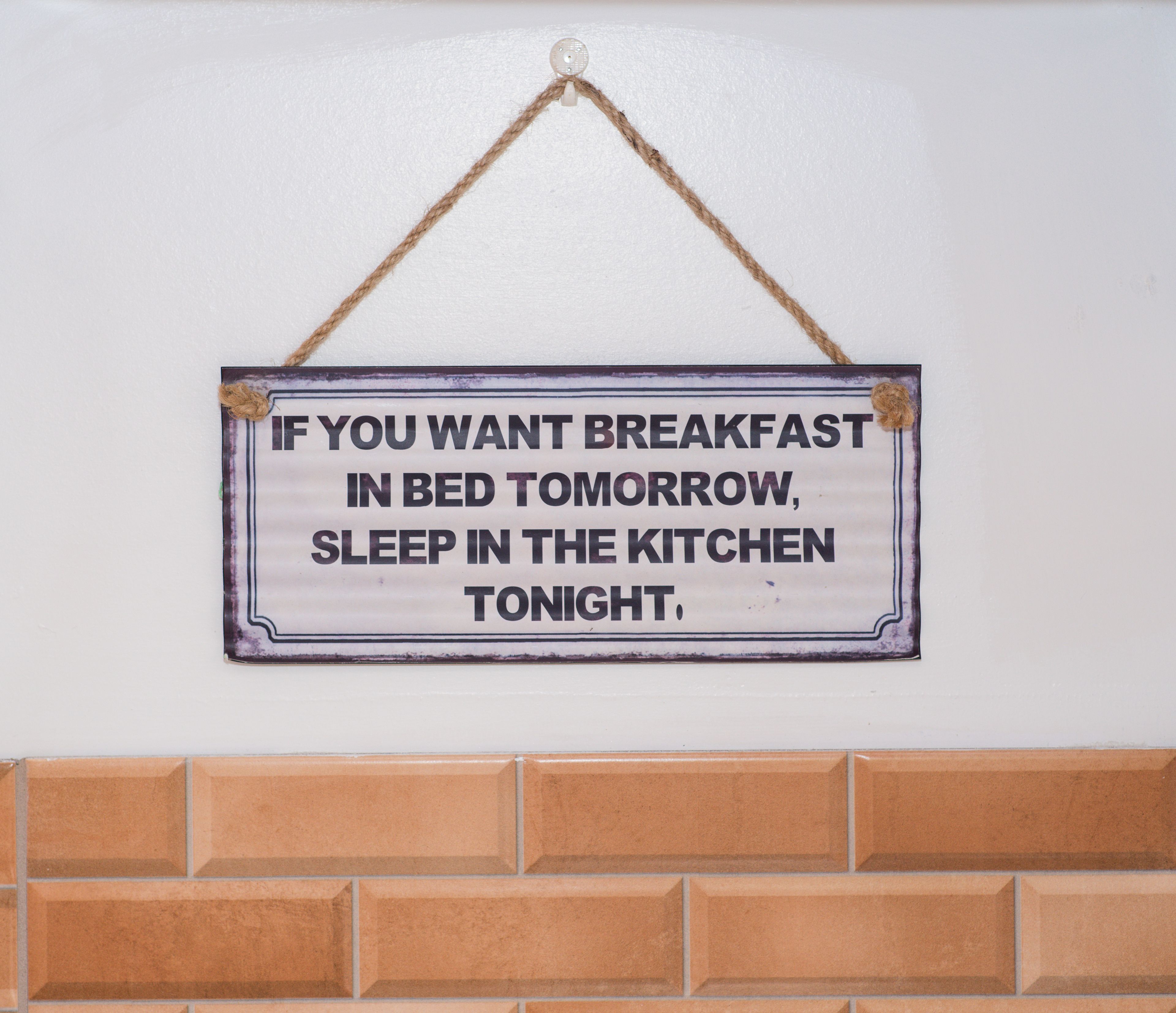 A sign with a humorous message about breakfast and sleeping arrangements.