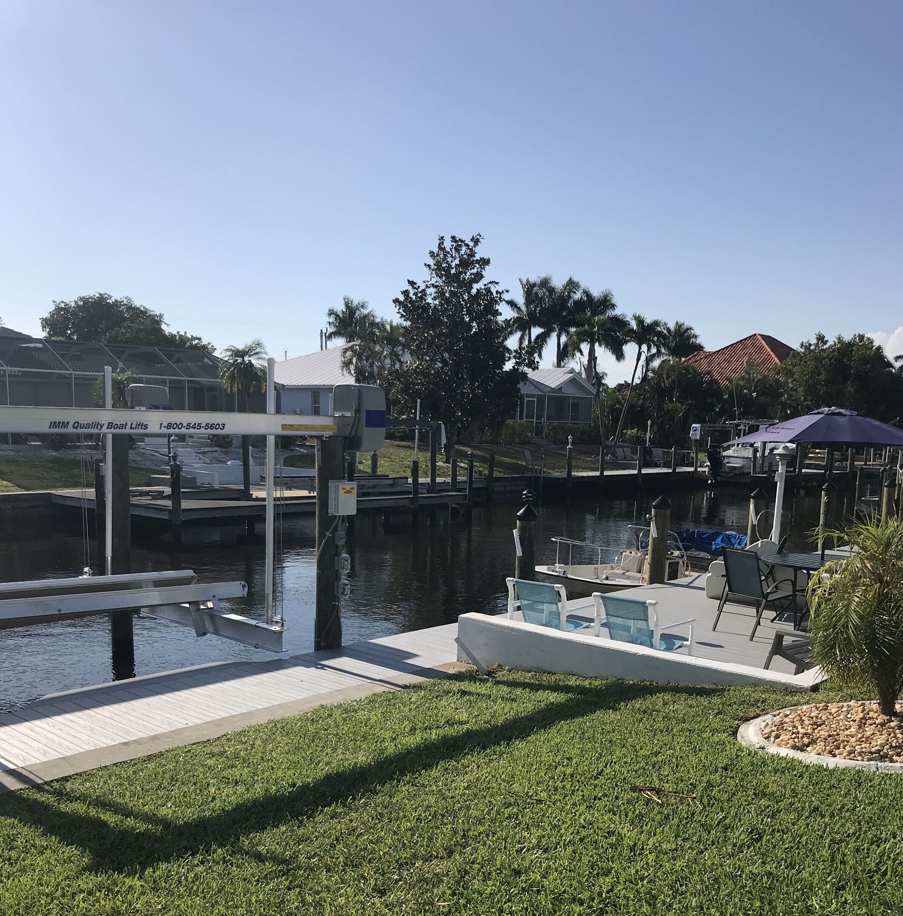 A marina with a boat lift, a dock with a boat, and a small building with a sign.
