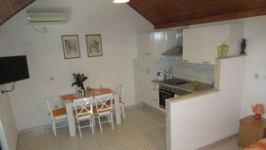 Une cuisine compacte avec des meubles blancs, une table à manger avec des chaises et un petit îlot central.