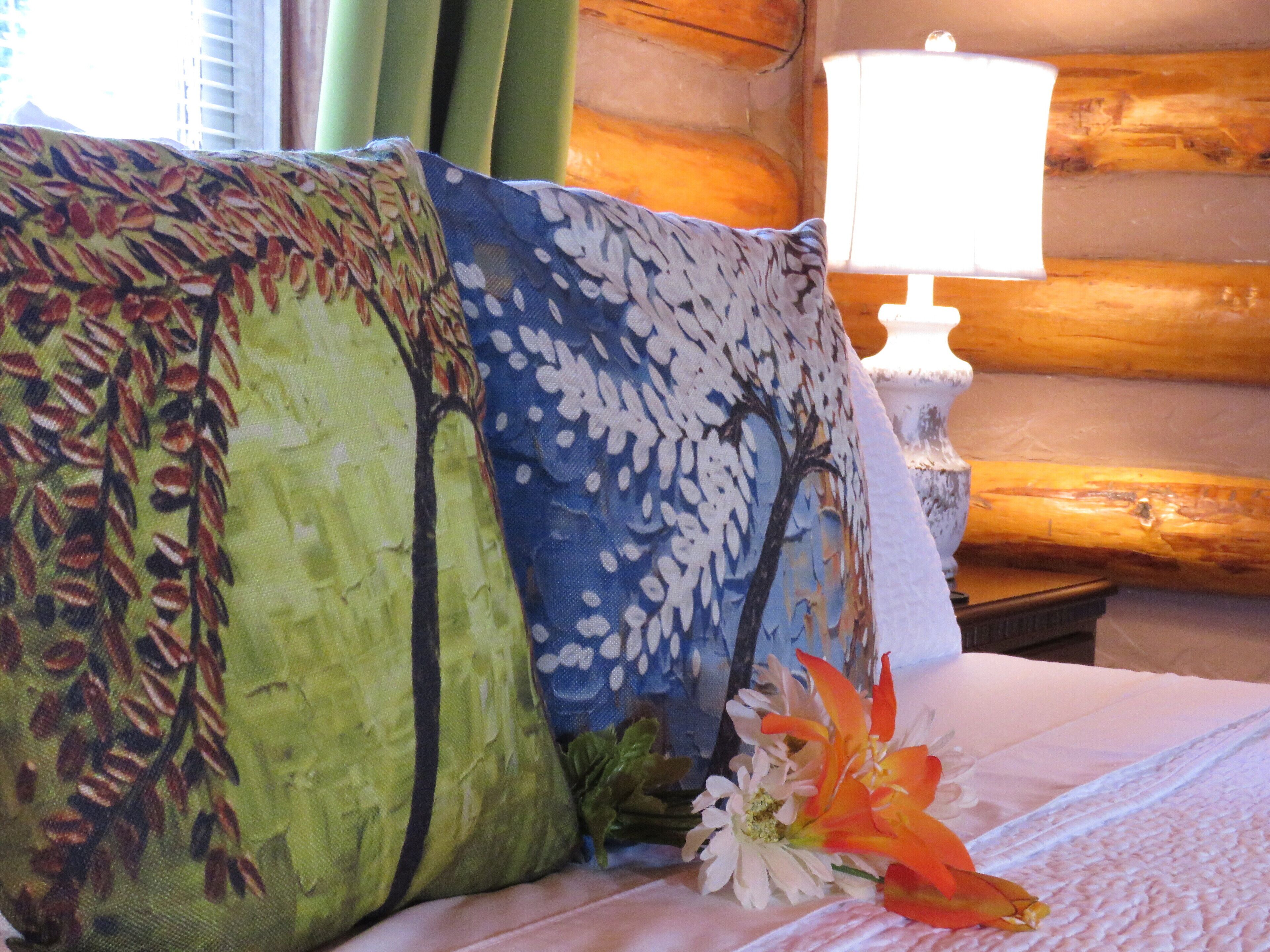 A bed with a floral pillow, a white lamp, and a window with curtains.