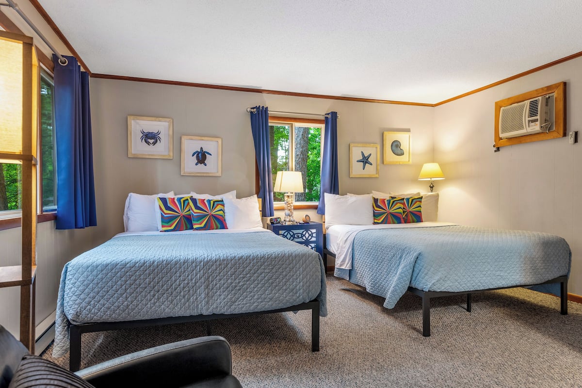 A hotel room with two beds, a desk, and a chair.