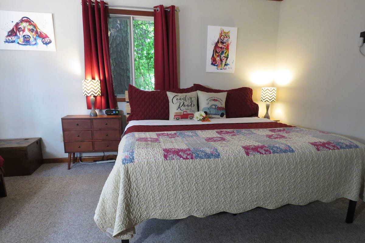 A bedroom with a bed, a nightstand, a dresser, and two wall art pieces.