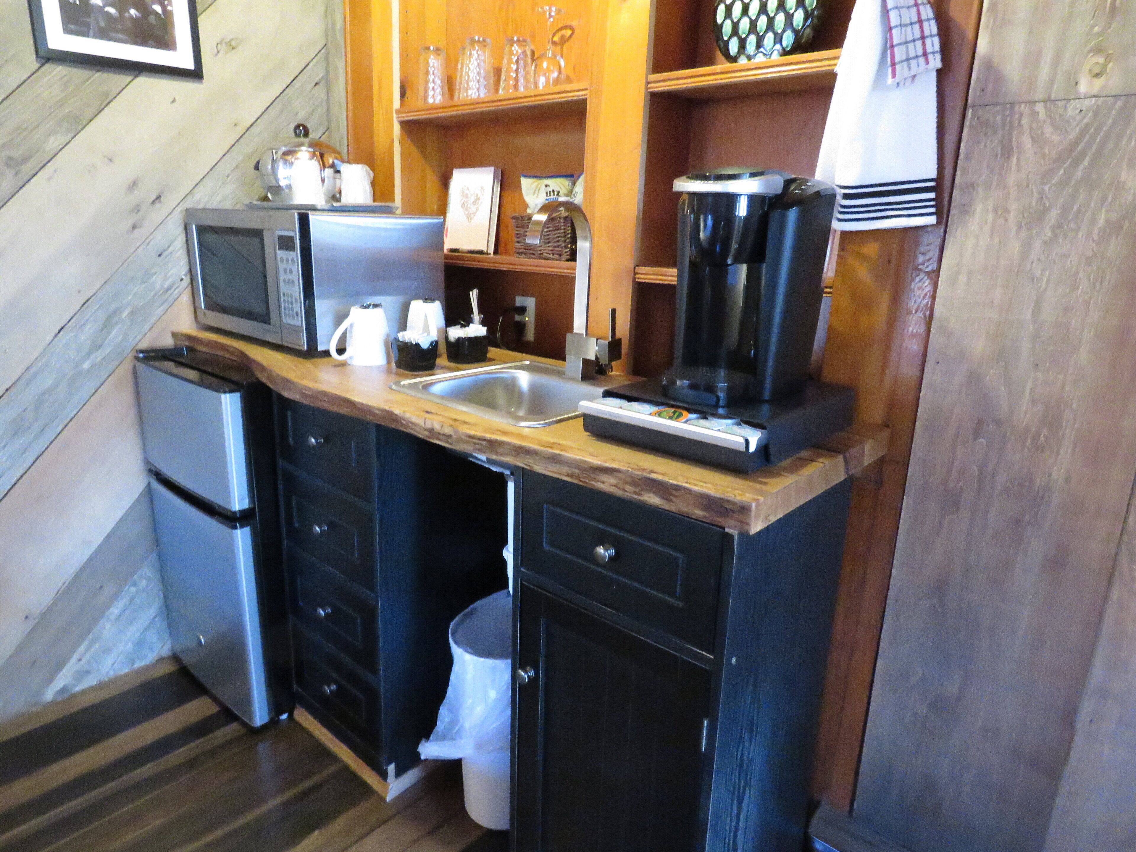 A compact kitchen with a microwave, coffee maker, and a small refrigerator.