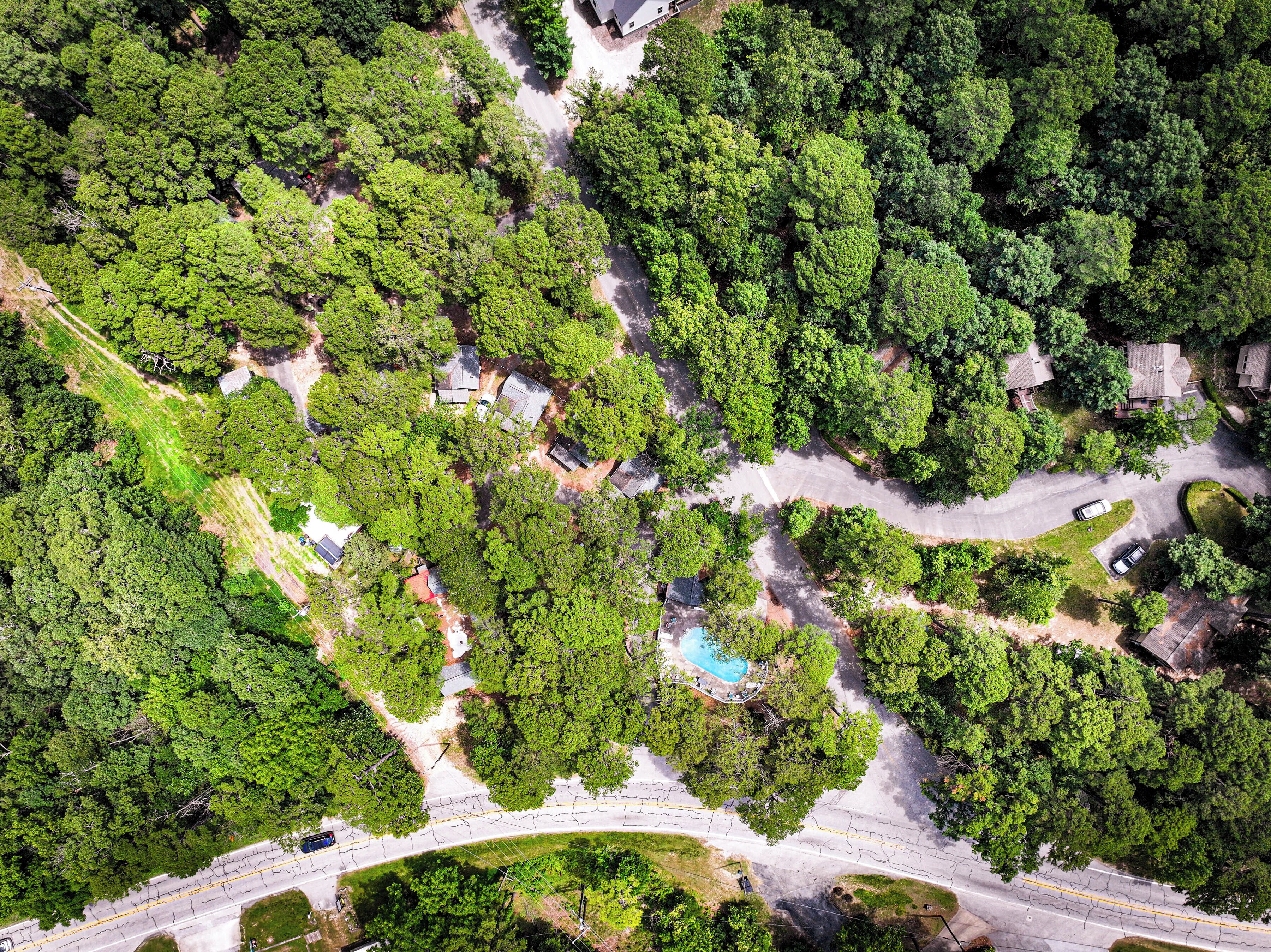 Vista aerea di una zona residenziale con case, strade e una piscina.