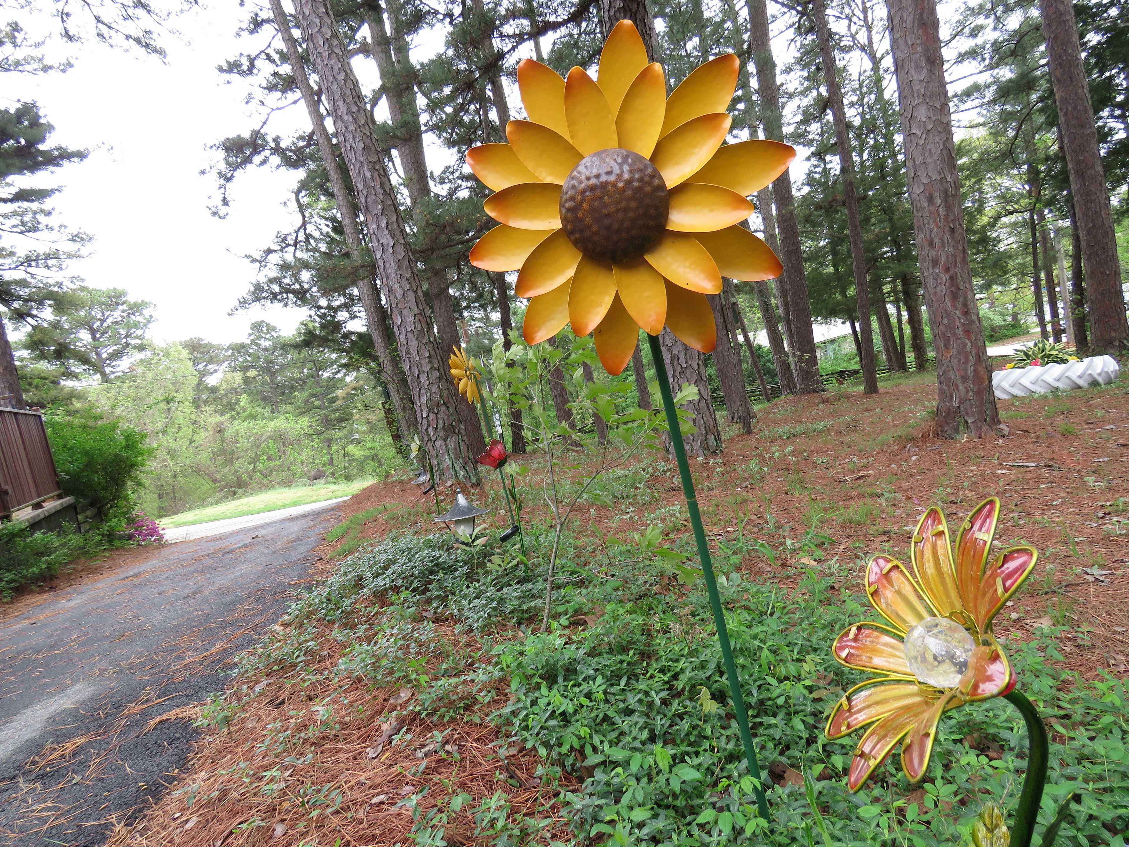 A garden with artificial flowers and a road.