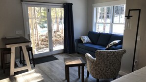 Una habitación con un sofá, un sillón estampado, una mesita y una cama.