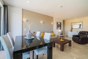 A modern living room with a dining table, sofa, and armchairs. - Marina Vilamoura - Aquamar 401- Modern Apartment (Quarteira)