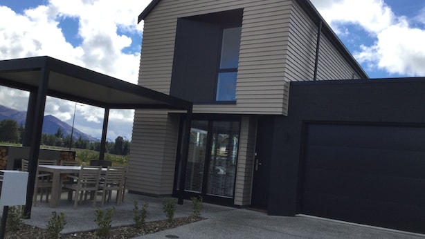 A modern house with a covered patio, a garage, and a mountain view. - Northlake Wanaka New Zealand. House to let in Ski Season. (Wanaka)