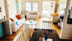 A spacious living area with a wooden dining table, white sofas, and a kitchen area with a stove. - West Dennis Central - 5 bed, 3 bath, 2 kitchen huge yard!
Two hot tubs! (Dennis)