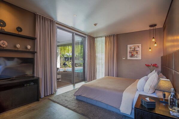 A modern hotel room with a large bed, a flat-screen TV, a bedside table with a lamp, and a view of a pool through a sliding glass door.