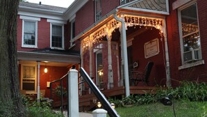A red brick building with a covered porch adorned with string lights. - Historic, quiet, elegant, mix of modern & original (Dubuque)