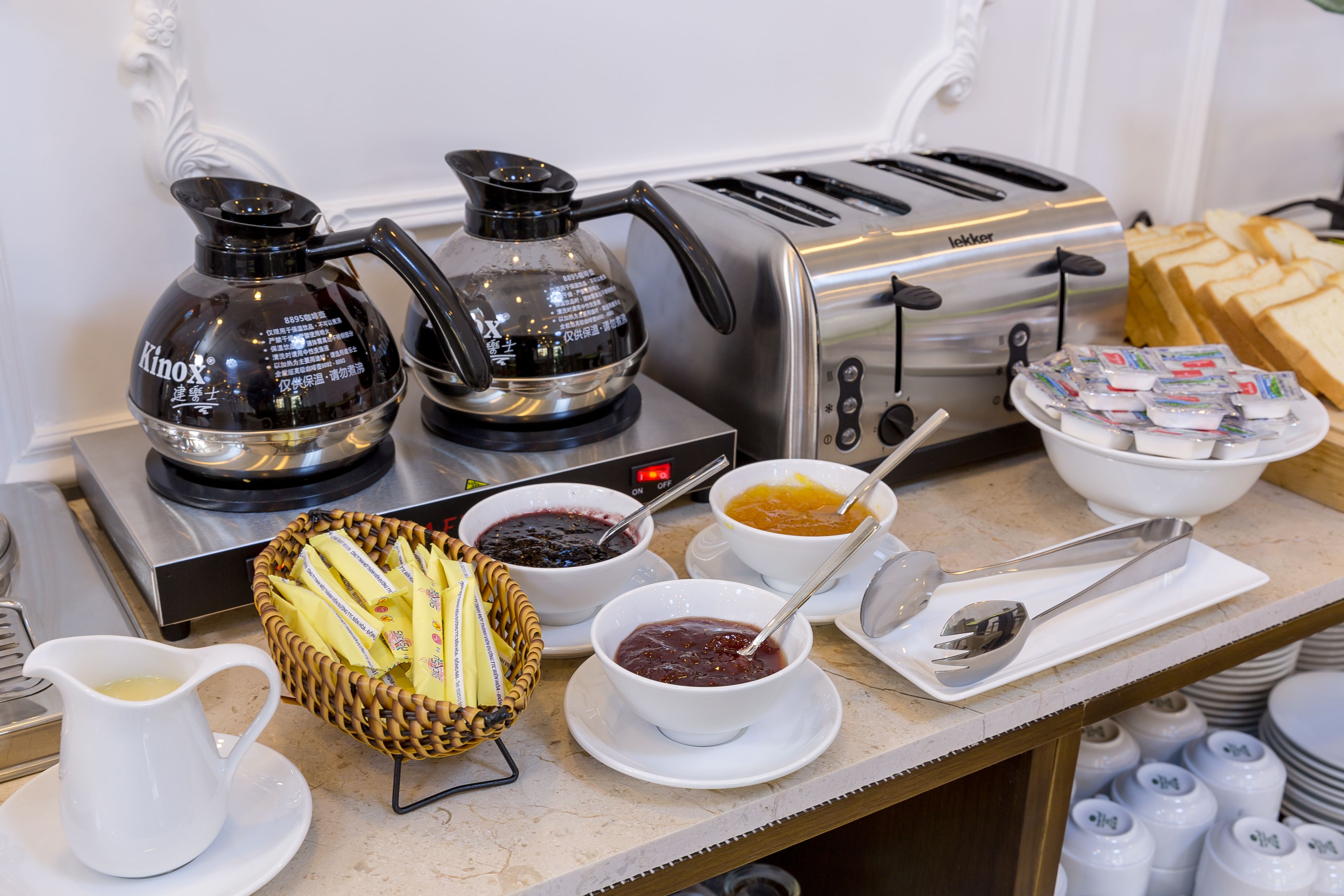 A breakfast buffet setup with coffee makers, toaster, and various food items.