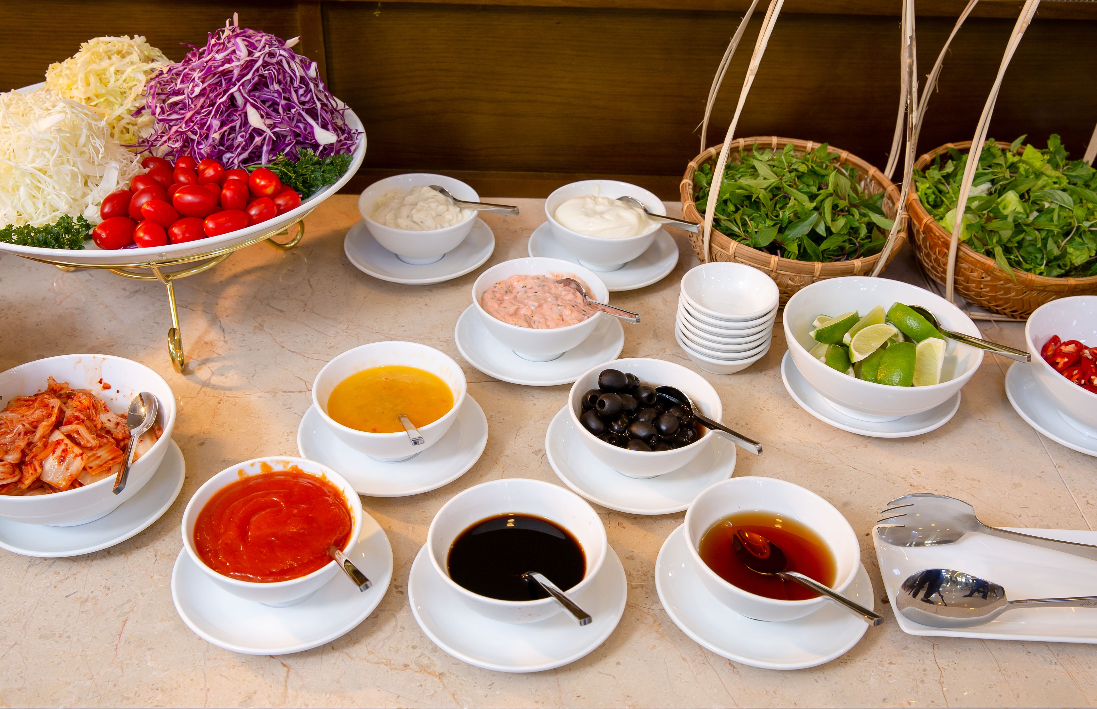 A buffet table with various dishes including salads, soups, and sauces.