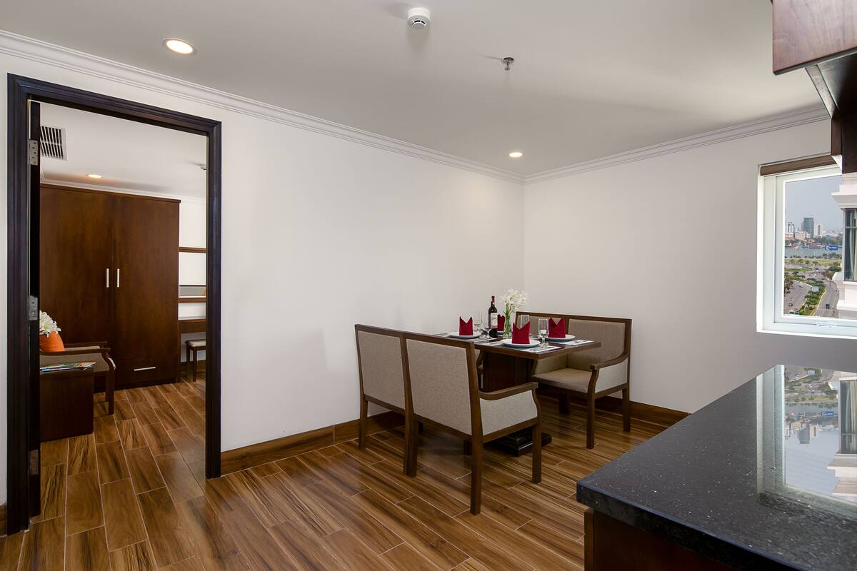 A modern dining area with a wooden floor, a table set for two, and a view of the city through a window.