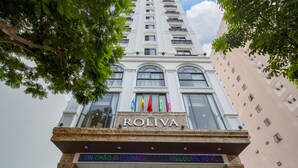 Entrada de un hotel con un cartel con el nombre, varias banderas y una escalera que sube.