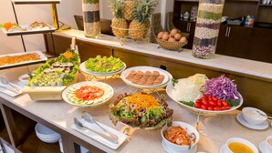 Un bufé con diversos platos, incluyendo ensaladas, sándwiches y frutas.