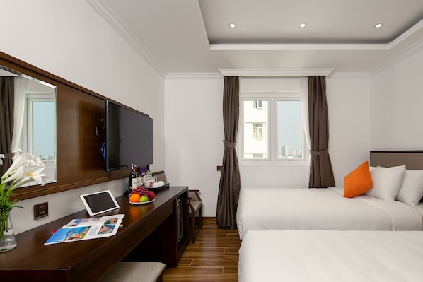 Une chambre d’hôtel avec un lit, un bureau avec un ordinateur portable, une télévision et une fenêtre avec des rideaux.