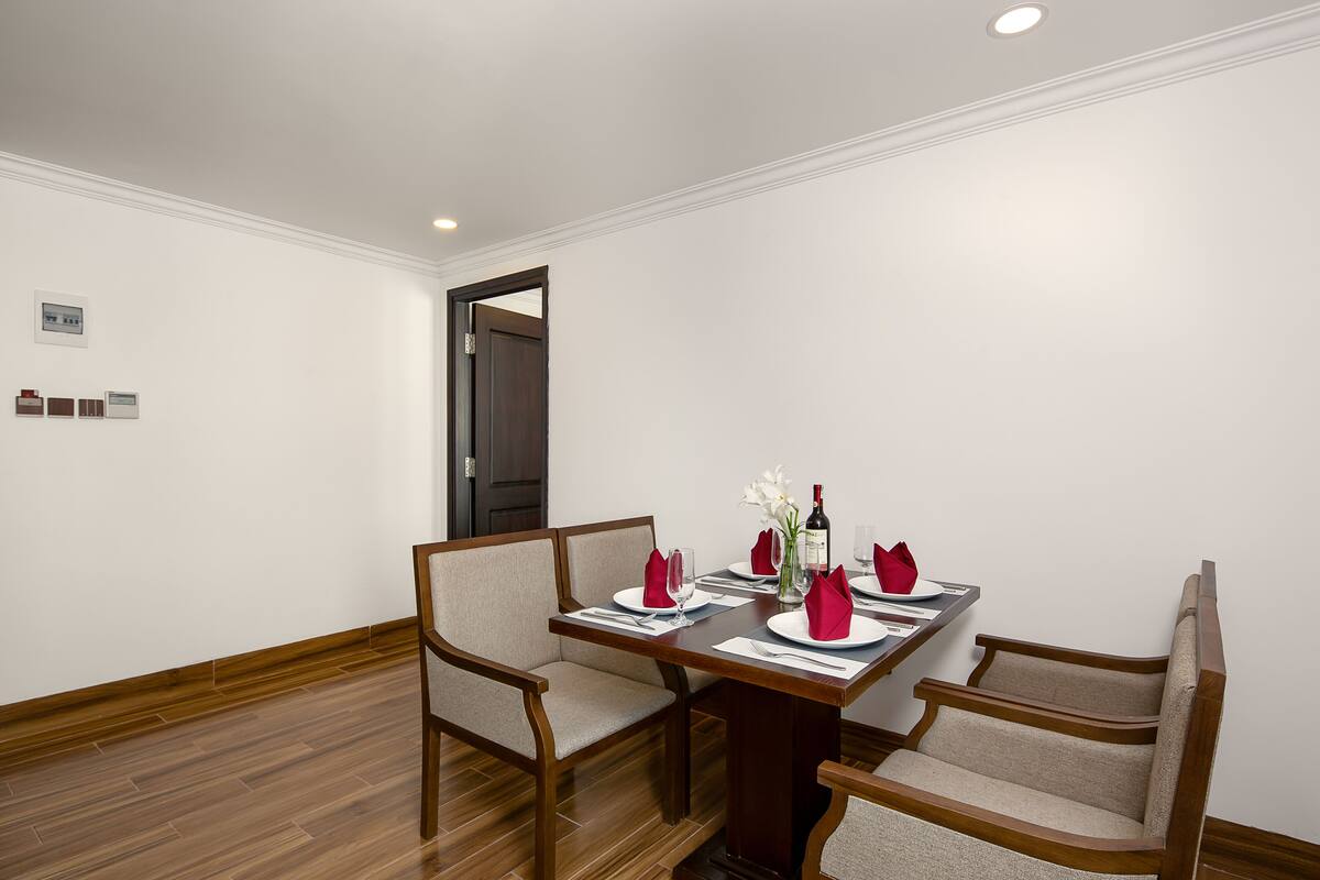 A dining area with a wooden table, four chairs, and a dark wooden door.
