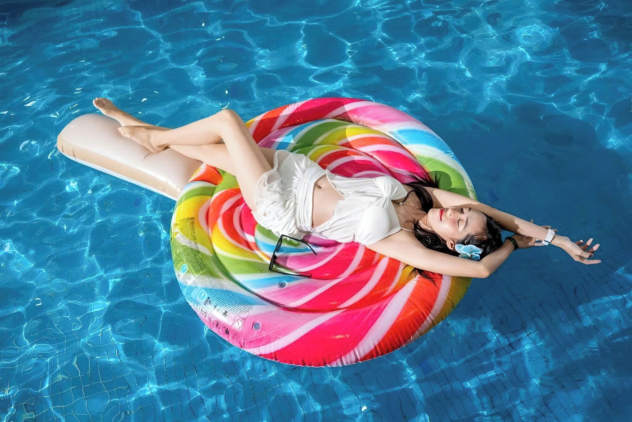A person floating on a colorful inflatable ring in a swimming pool.