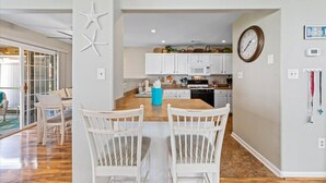 A modern kitchen with white cabinets, a wooden countertop, and a clock on the wall.