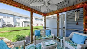A covered patio with wicker furniture, a ceiling fan, and a view of neighboring houses.