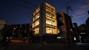 Un edificio de varios pisos con ventanas iluminadas al anochecer.
