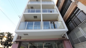 Un edificio de varios pisos con fachada blanca, ventanas grandes y balcones.