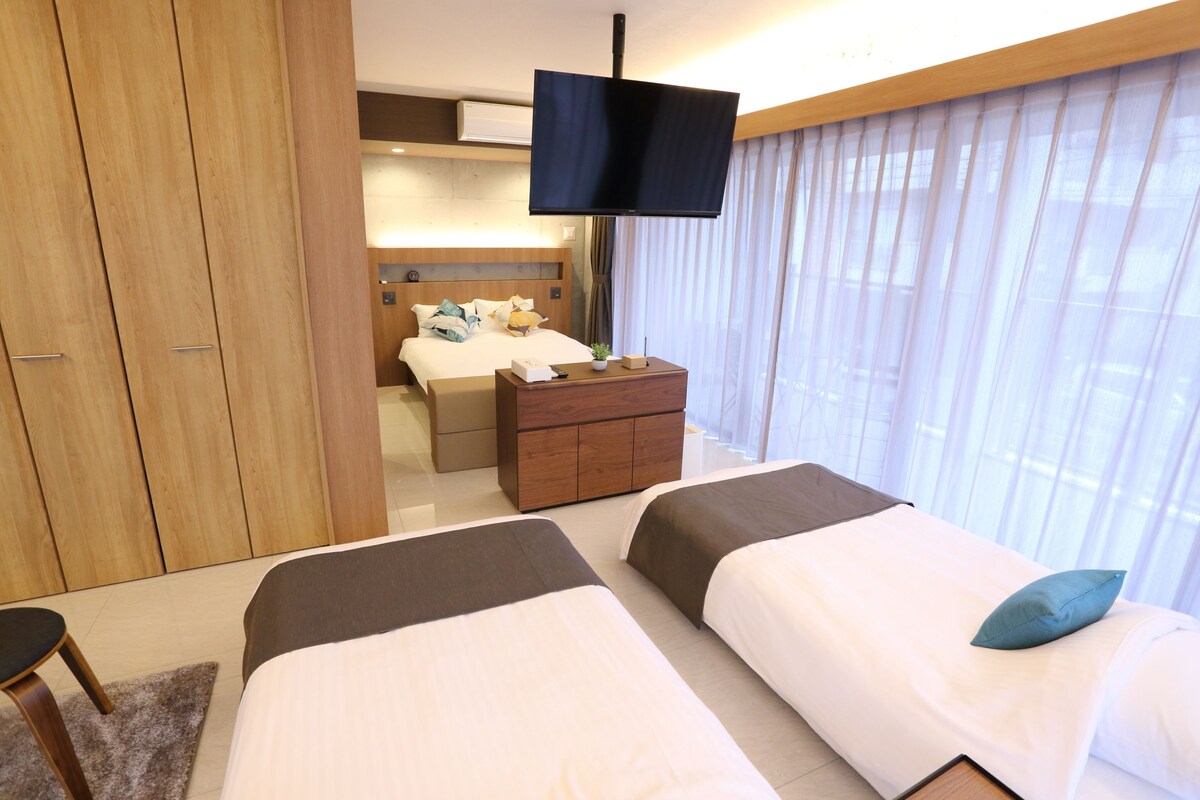Une chambre d’hôtel avec deux lits, une télévision, une armoire en bois et une table de chevet.