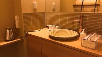 A bathroom with a round sink, a mirror, and a towel rack.
