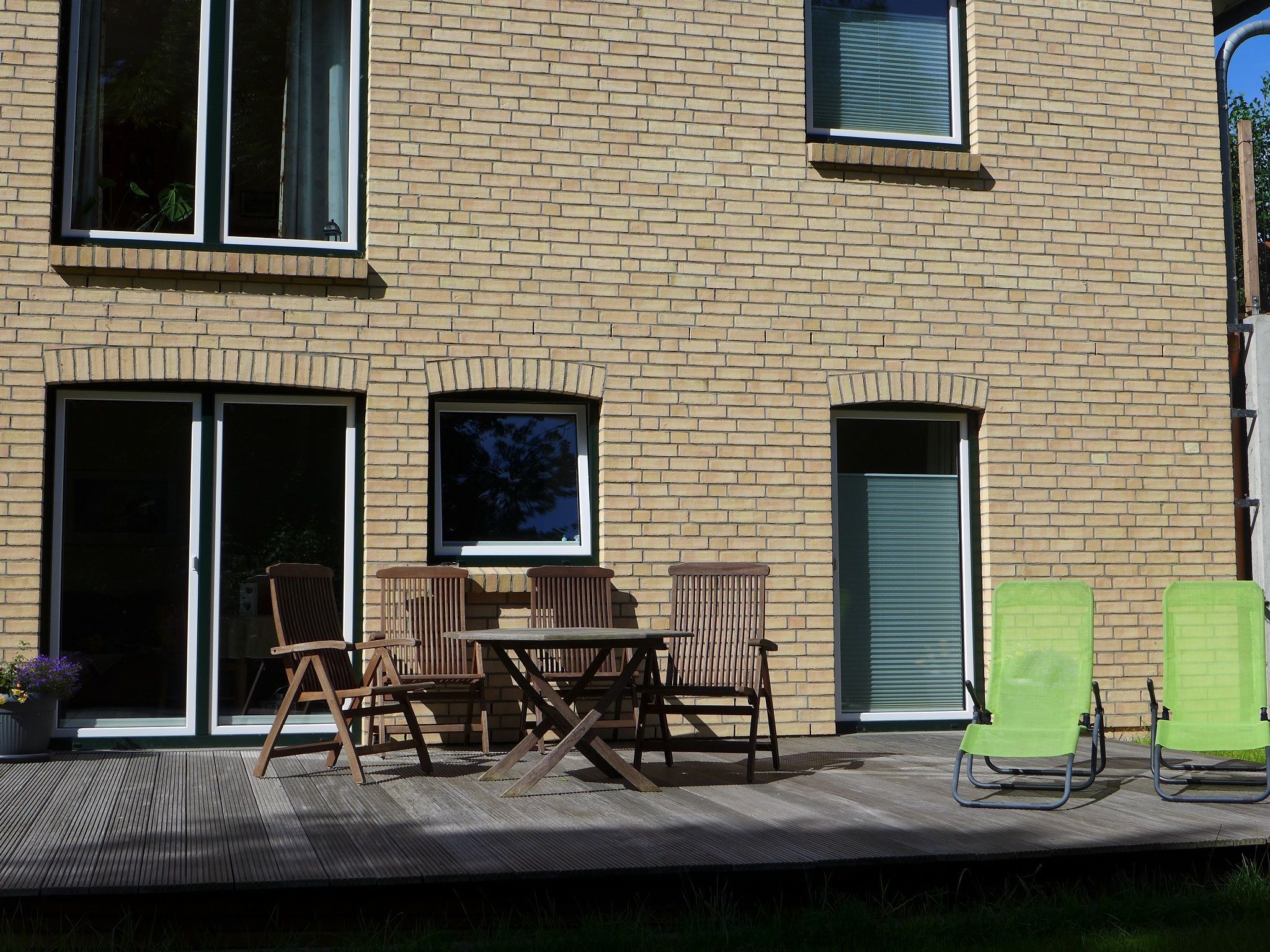 Un bâtiment en briques doté d’un patio aménagé avec du mobilier d’extérieur, notamment une table et des chaises, et une porte-fenêtre coulissante.