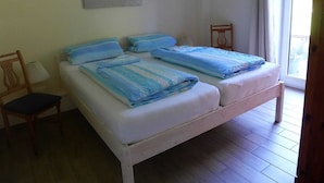 Une chambre avec deux lits, une chaise, une lampe et un tableau au mur.