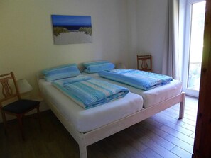 Une chambre avec deux lits, une chaise, une lampe et un tableau au mur.