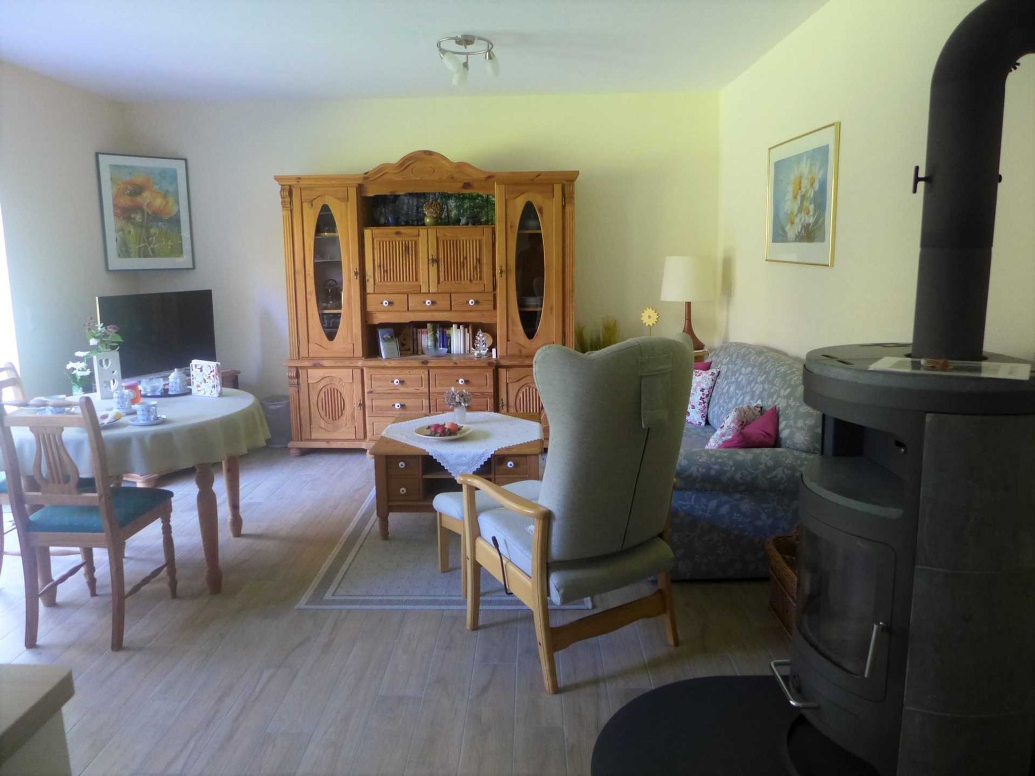 Una sala de estar con un aparador de madera, un sofá, una mesa con sillas y una chimenea.
