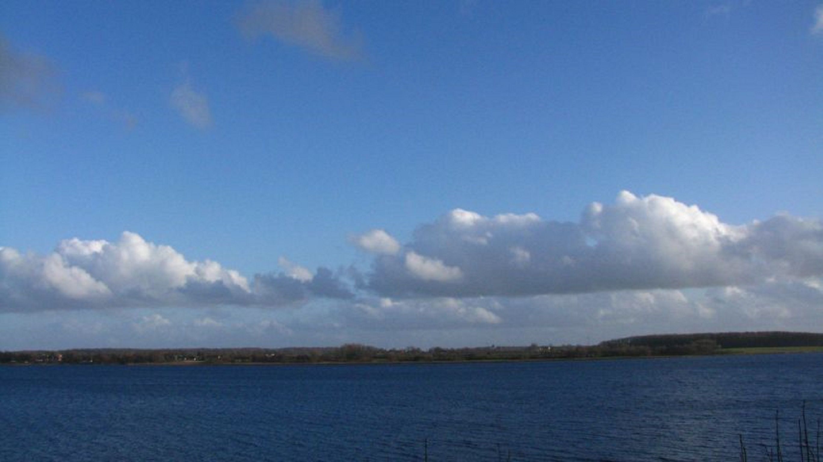 A body of water with a distant shoreline and a clear sky.
