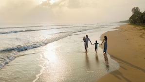 Una escena de playa con una familia caminando por la orilla.