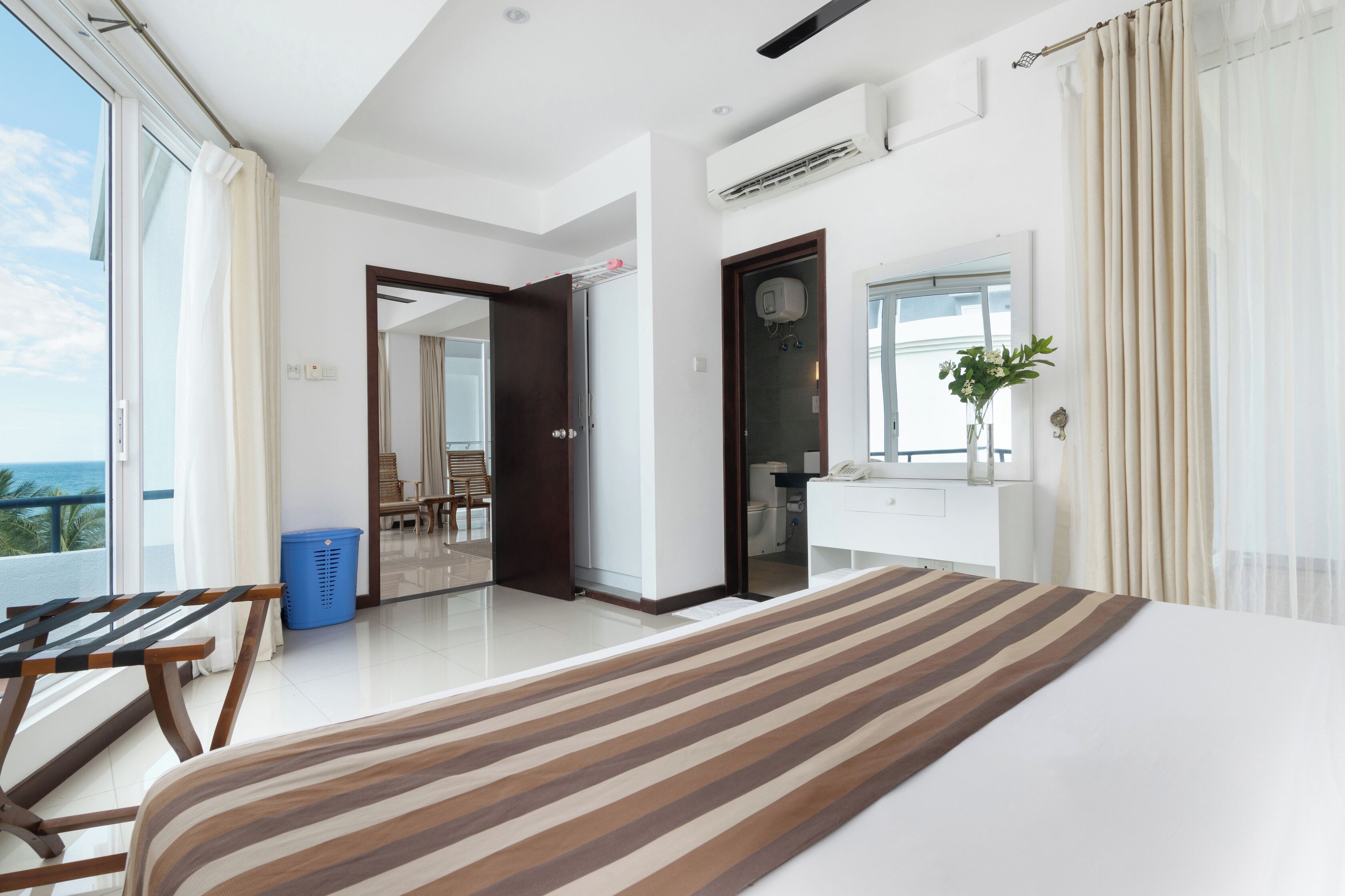 A hotel room with a large bed, a balcony with a view, a bathroom, and a dining area.