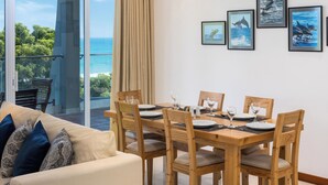 Una sala de estar moderna con un sofá, una mesa de comedor y sillas, un ventilador de techo y cuadros en la pared.