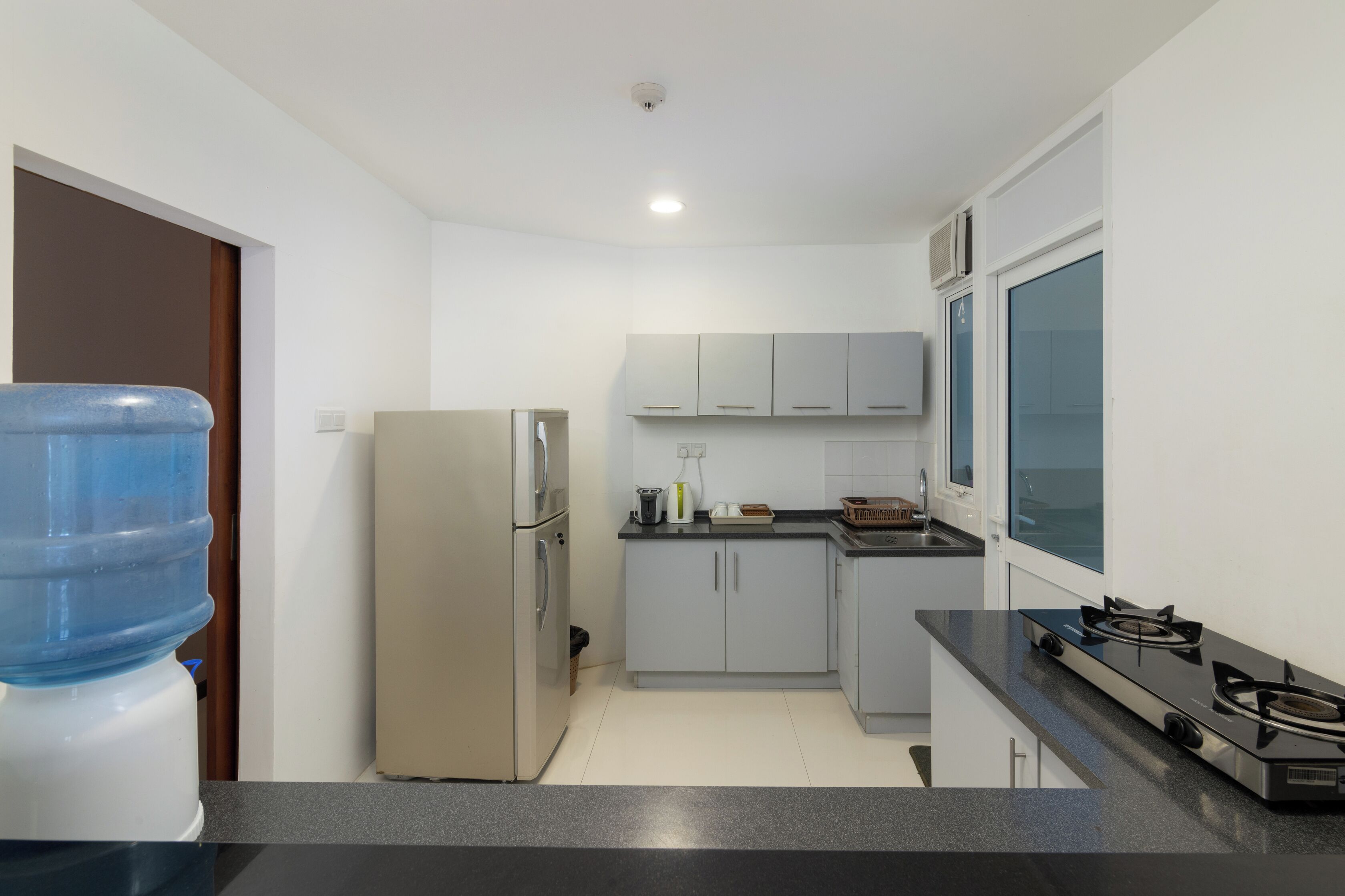 Cocina compacta con refrigerador, estufa y dispensador de agua.