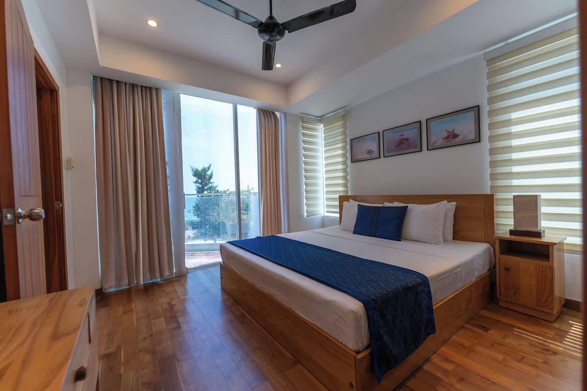 A modern bedroom with a large bed, wooden headboard, and a ceiling fan.
