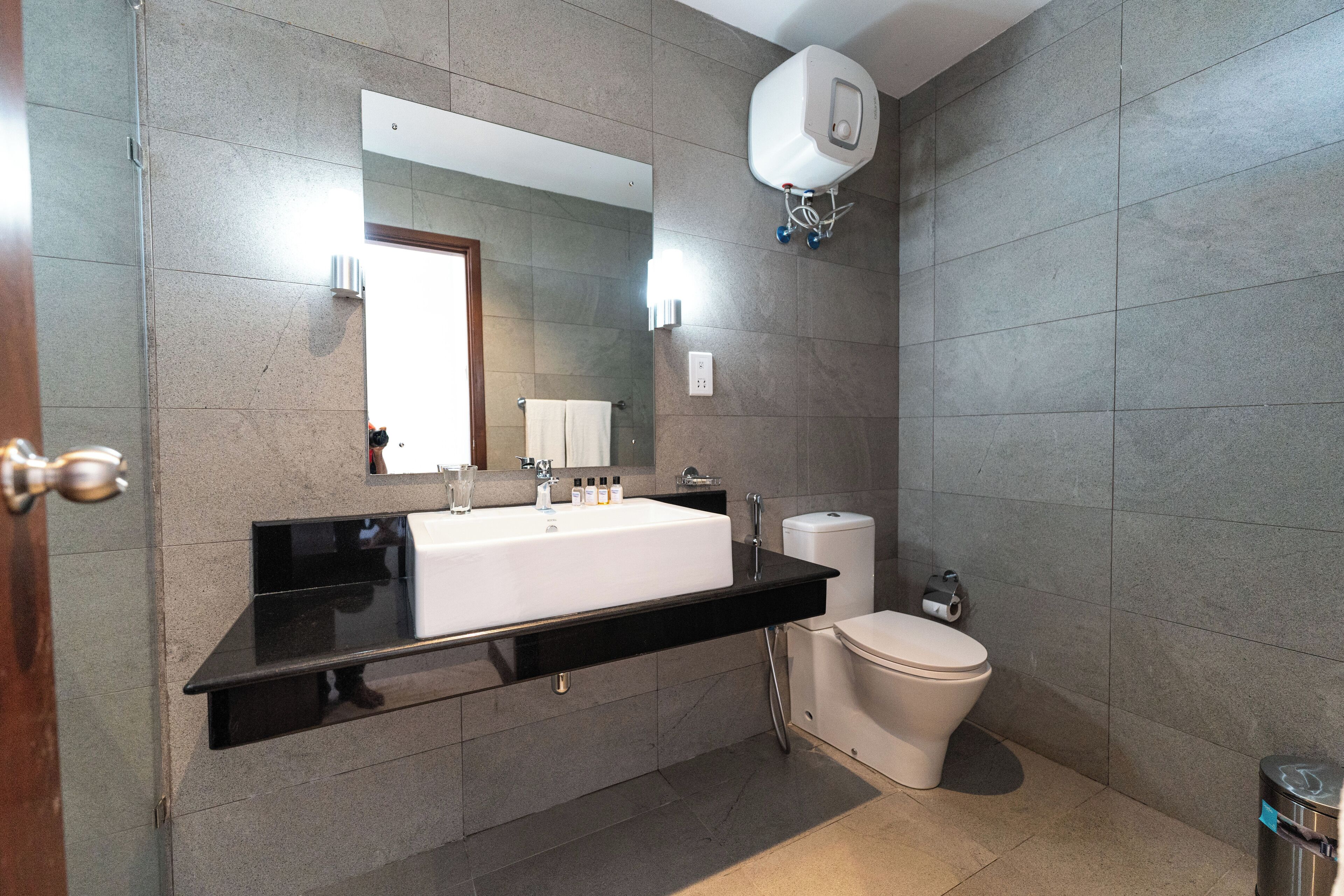 A modern bathroom with a black countertop, white sink, and a toilet.
