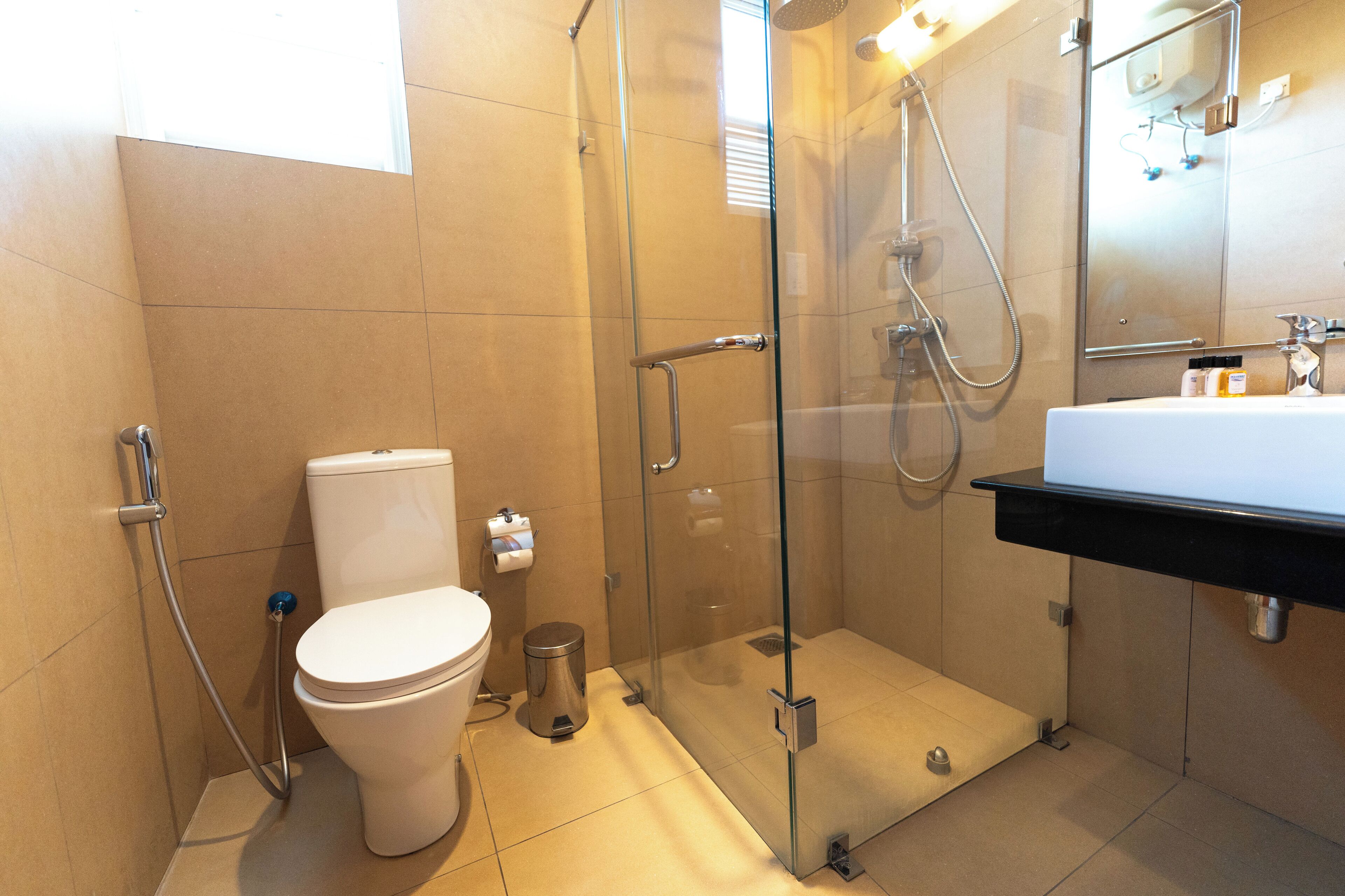 A modern bathroom with a glass-enclosed shower, a white toilet, and a black sink vanity.