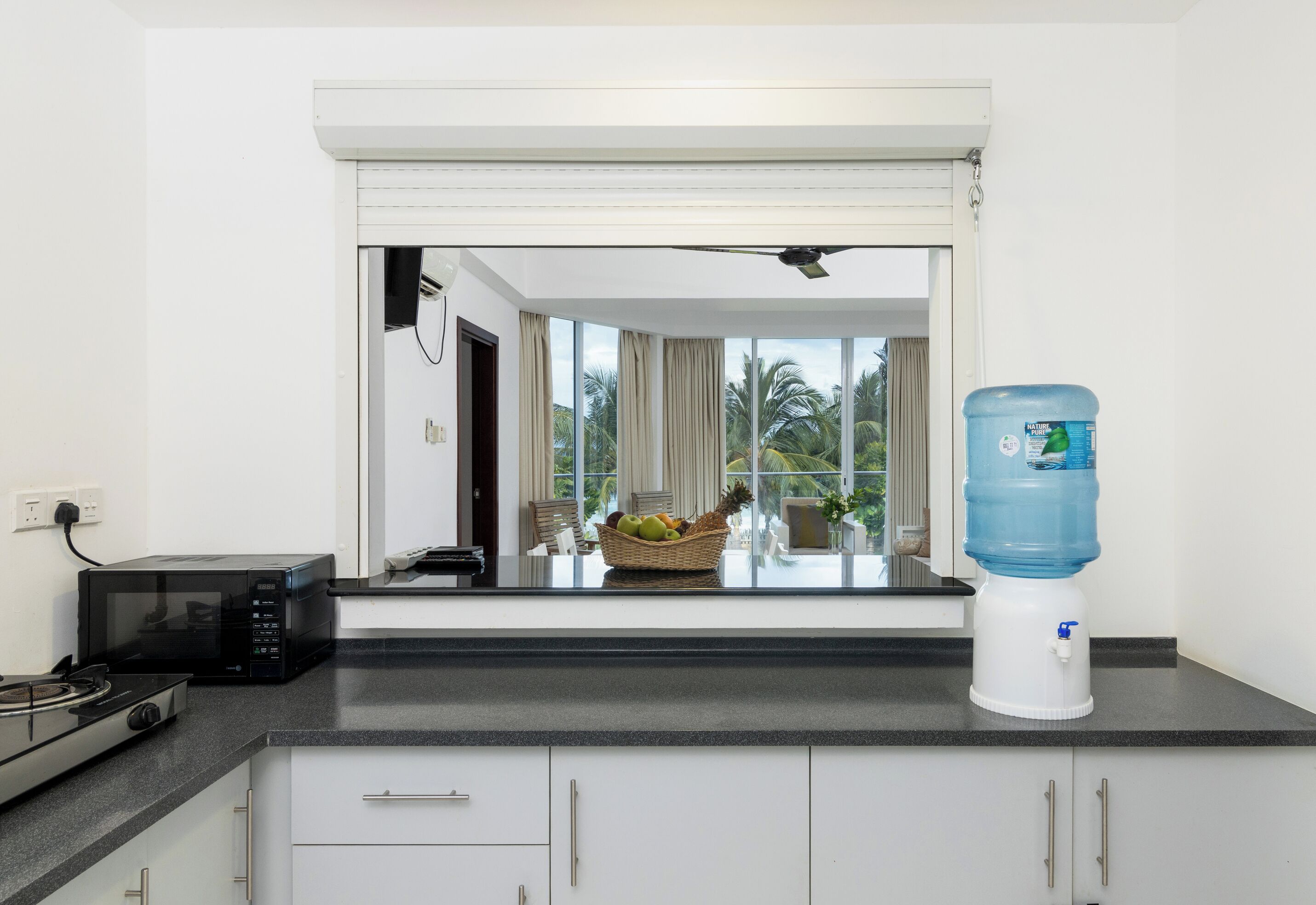 A modern kitchen with a microwave, stove, and water dispenser.
